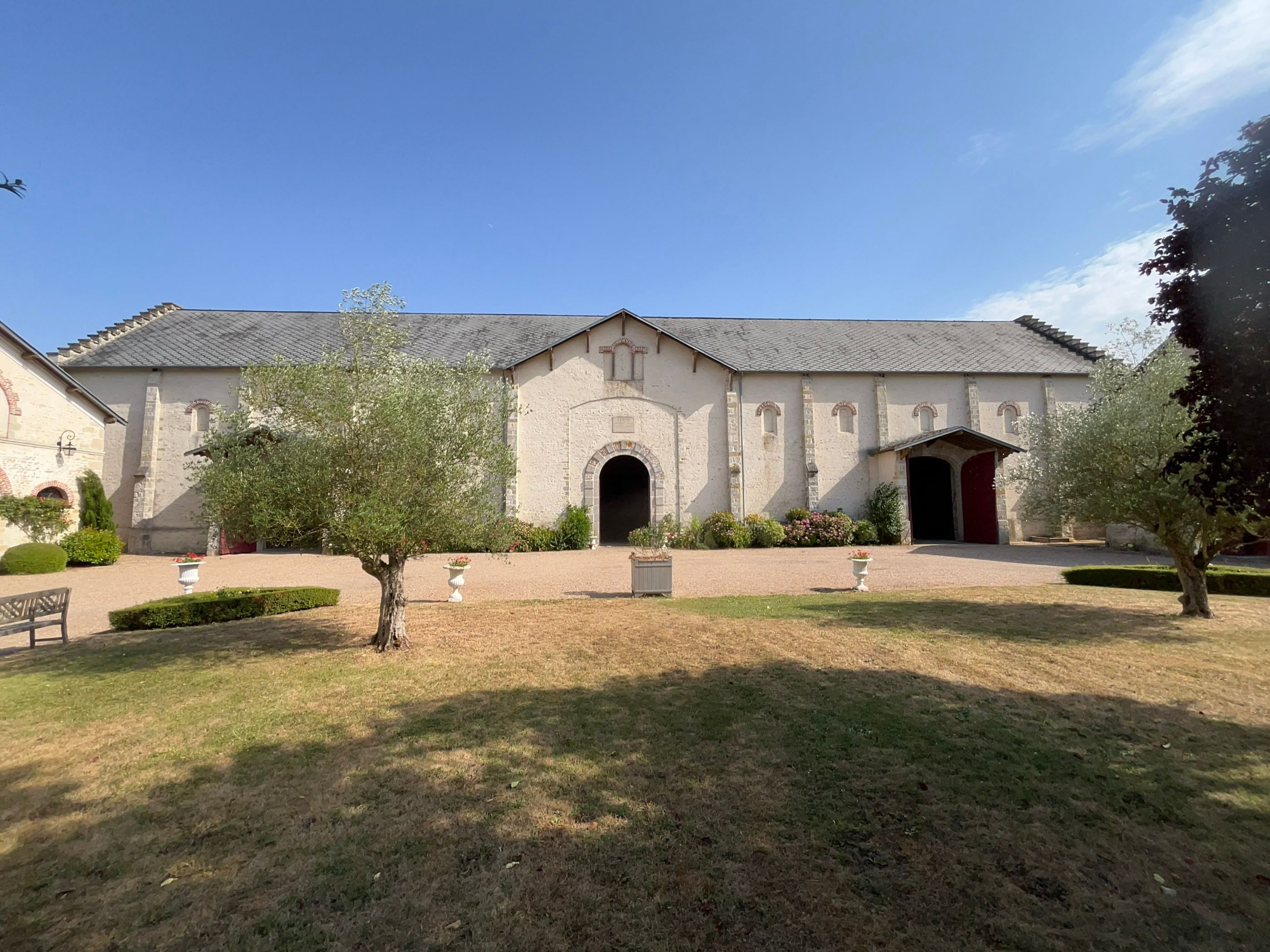La façade de La Grange vue depuis le milieu de la cour, pierre blonde et grande porte cintrée